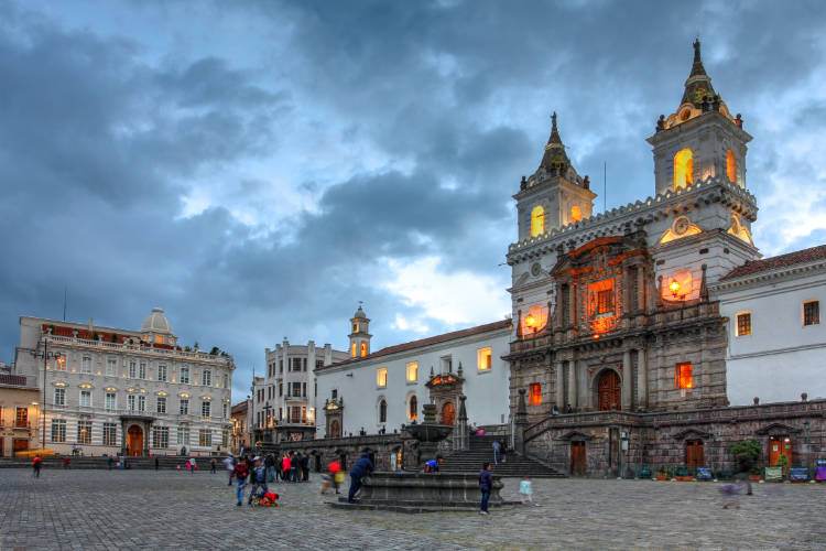 Una plaza con una iglesia y una torre del reloj al fondo.