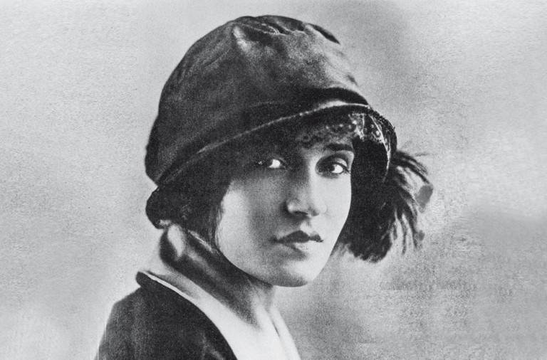 Un retrato vintage en blanco y negro de una mujer con un sombrero cloche, mirando hacia la cámara con una expresión neutra.